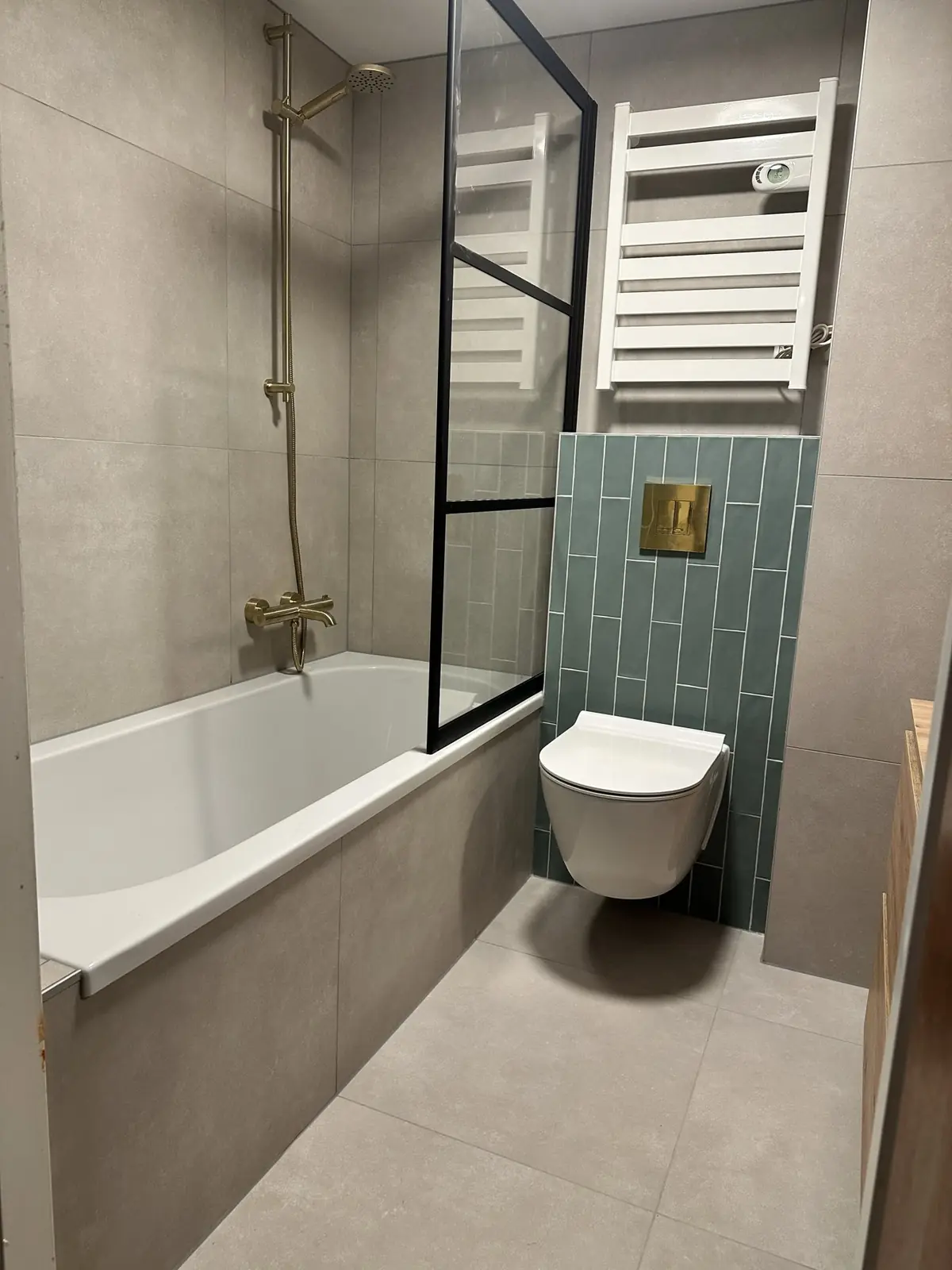 Badkamer met ligbad en groene tegelwand in Wageningen