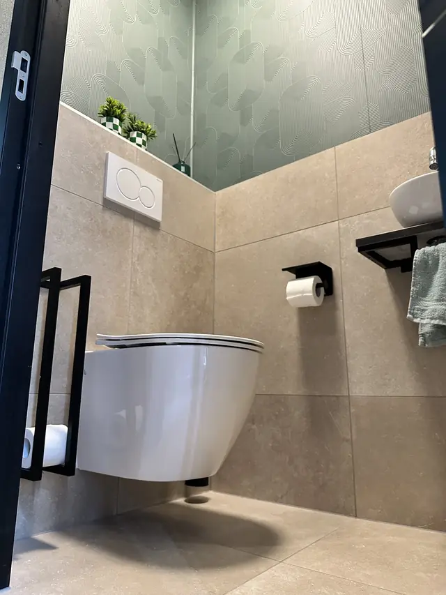 Toilet met groen behang en natuursteentegels, foto 4 van 7